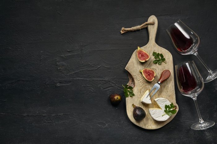 two-glasses-red-wine-tasty-cheese-plate-with-fruit-wooden-kitchen-plate-black-stone